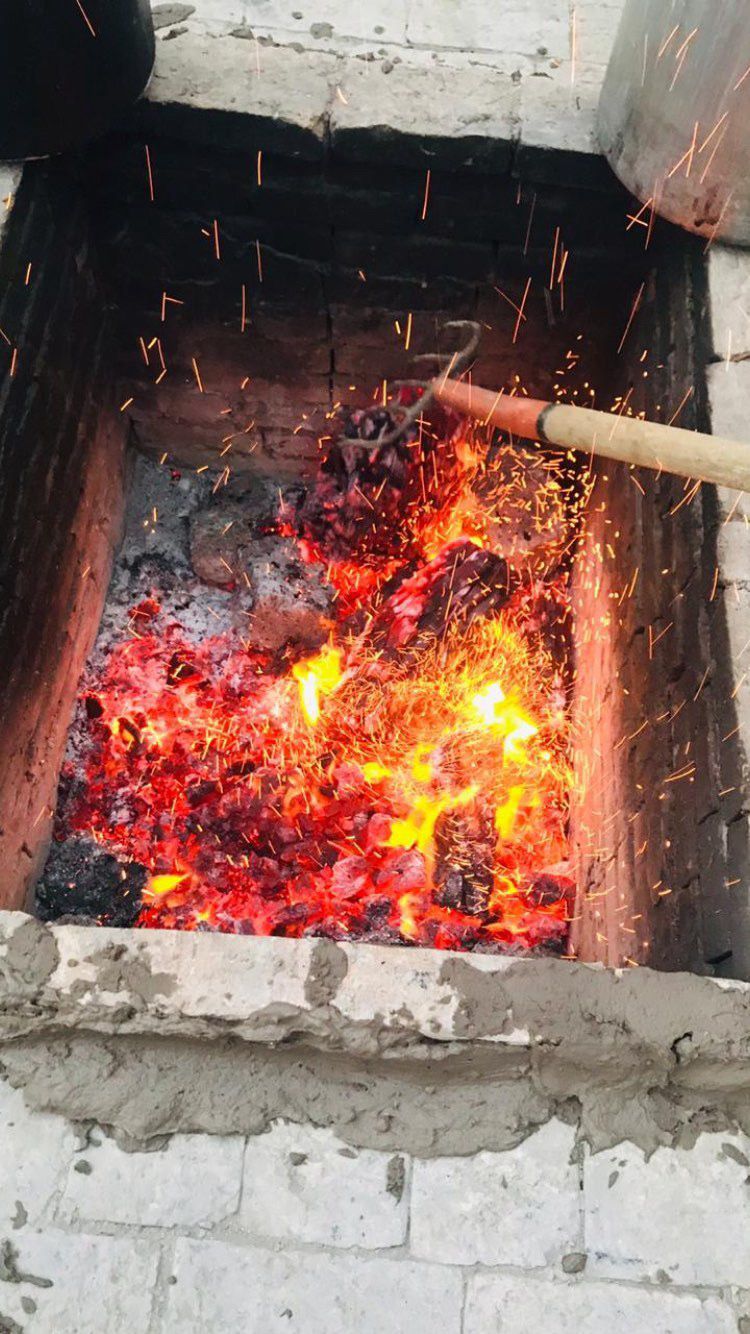 Brasas encendidas con chispas volando y pala de madera