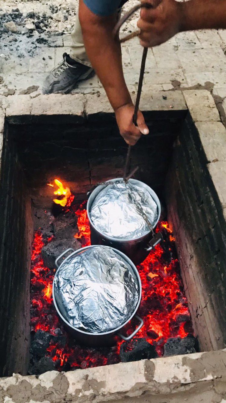 Ollas de aluminio bajando al pozo con brasas y fuego