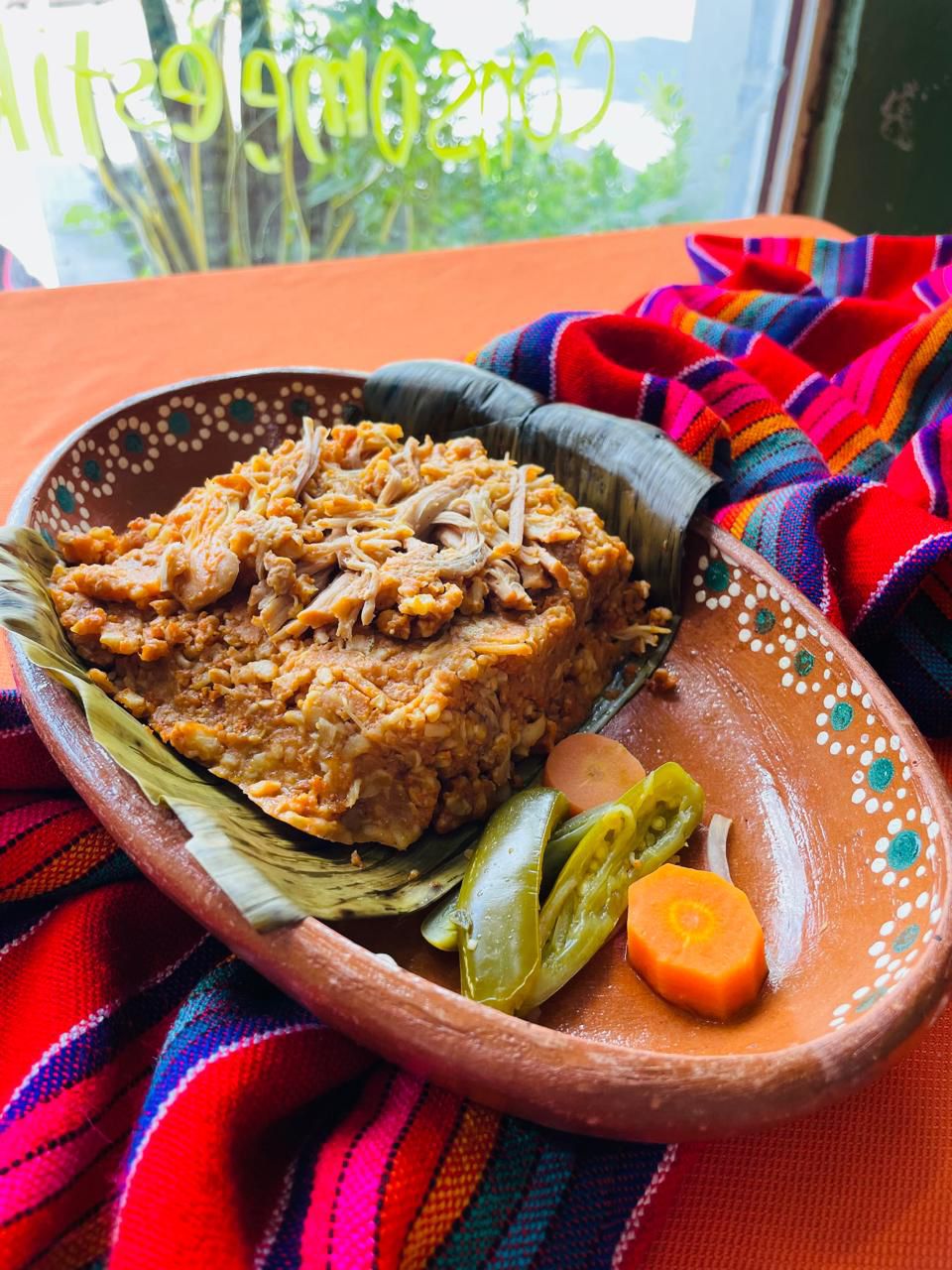 Zacahuil servido en plato de barro con jalapeños y zanahoria